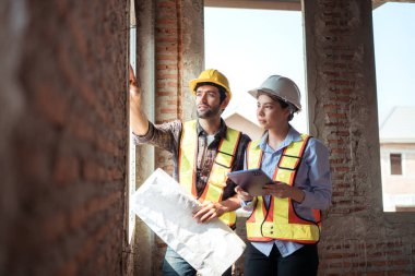 Mimarlar ve mühendisler, konut inşaatının ilerlemesini değerlendirmek için birlikte çalışırlar.