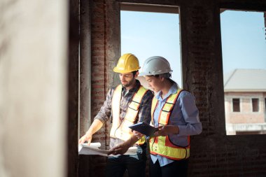 Mimarlar ve mühendisler, konut inşaatının ilerlemesini değerlendirmek için birlikte çalışırlar.