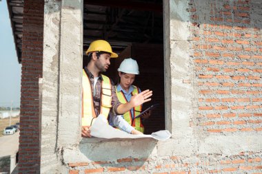 Mimarlar ve mühendisler, konut inşaatının ilerlemesini değerlendirmek için birlikte çalışırlar.