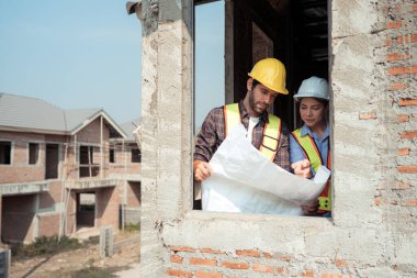 Mimarlar ve mühendisler, konut inşaatının ilerlemesini değerlendirmek için birlikte çalışırlar.