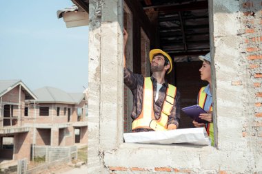 Mimarlar ve mühendisler, konut inşaatının ilerlemesini değerlendirmek için birlikte çalışırlar.
