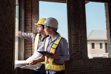 Mimarlar ve mühendisler, konut inşaatının ilerlemesini değerlendirmek için birlikte çalışırlar.