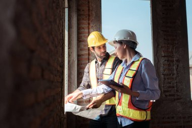 Mimarlar ve mühendisler, konut inşaatının ilerlemesini değerlendirmek için birlikte çalışırlar.