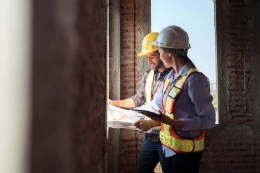 Mimarlar ve mühendisler, konut inşaatının ilerlemesini değerlendirmek için birlikte çalışırlar.
