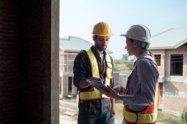 Mimarlar ve mühendisler, konut inşaatının ilerlemesini değerlendirmek için birlikte çalışırlar.