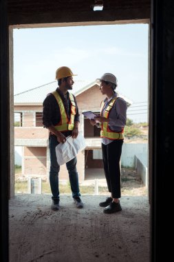 Mimarlar ve mühendisler, konut inşaatının ilerlemesini değerlendirmek için birlikte çalışırlar.