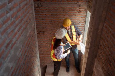 Mimarlar ve mühendisler, konut inşaatının ilerlemesini değerlendirmek için birlikte çalışırlar.