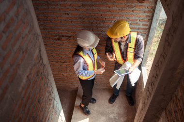 Mimarlar ve mühendisler, konut inşaatının ilerlemesini değerlendirmek için birlikte çalışırlar.