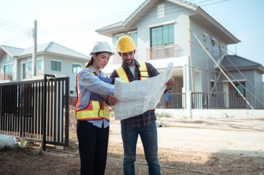 Mimarlar ve mühendisler, konut inşaatının ilerlemesini değerlendirmek için birlikte çalışırlar.