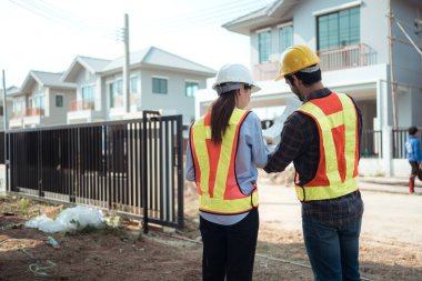 Mimarlar ve mühendisler, konut inşaatının ilerlemesini değerlendirmek için birlikte çalışırlar.