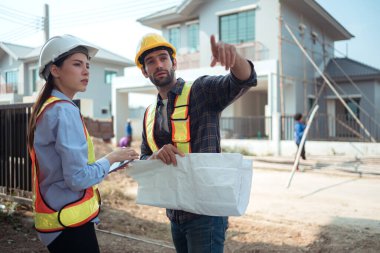 Mimarlar ve mühendisler, konut inşaatının ilerlemesini değerlendirmek için birlikte çalışırlar.