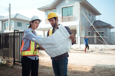 Mimarlar ve mühendisler, konut inşaatının ilerlemesini değerlendirmek için birlikte çalışırlar.