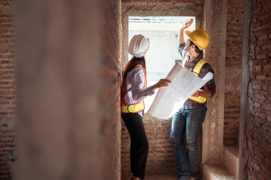 Mimarlar ve mühendisler, konut inşaatının ilerlemesini değerlendirmek için birlikte çalışırlar.