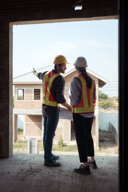 Mimarlar ve mühendisler, konut inşaatının ilerlemesini değerlendirmek için birlikte çalışırlar.