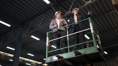 İş kadını ve depo çalışanları belgelere dayanarak listeyi inceliyorlar.