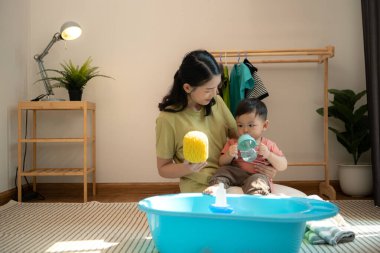 Annesiyle kahvaltı yapan küçük çocuk banyo yapmadan önce onu besliyor.