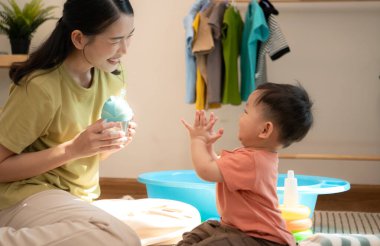 Annesiyle kahvaltı yapan küçük çocuk banyo yapmadan önce onu besliyor.