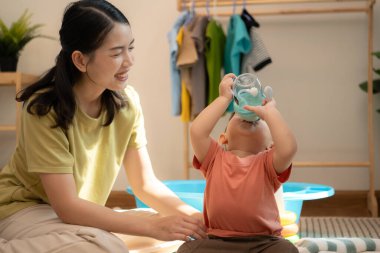 Annesiyle kahvaltı yapan küçük çocuk banyo yapmadan önce onu besliyor.