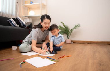 Evde tatildeyken, bir anne küçük çocukla aktiviteler çizer.