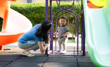 Evde tatildeyken, bir anne parkta küçük bir çocukla bir şeyler yapıyor.