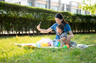 Evde tatildeyken, bir anne parkta küçük bir çocukla bir şeyler yapıyor.