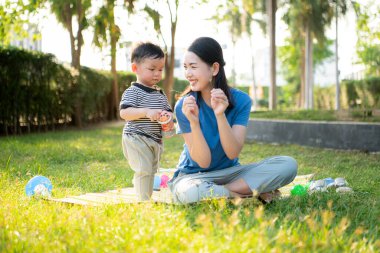 Evde tatildeyken, bir anne parkta küçük bir çocukla bir şeyler yapıyor.
