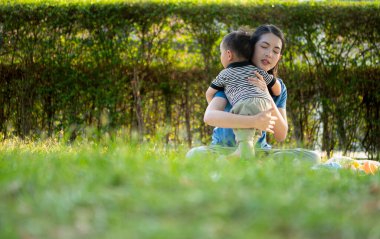 Evde tatildeyken, bir anne parkta küçük bir çocukla bir şeyler yapıyor.