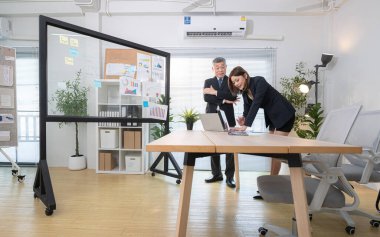 Çağdaş bir ofiste, patron ve asistan bir iş projesinin ilerlemesini izlemek için görevdeler.