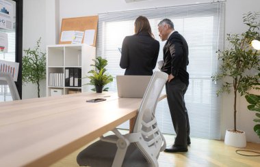 Çağdaş bir ofiste, patron ve asistan bir iş projesinin ilerlemesini izlemek için görevdeler.