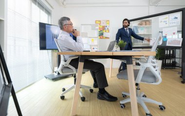 Çağdaş bir ofiste, iki üst düzey yönetici bir iş projesinin ilerleyişini izlemek ve beyin fırtınası yapmak istiyor.