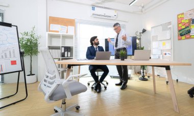 Çağdaş bir ofiste, iki üst düzey yönetici bir iş projesinin ilerleyişini izlemek ve beyin fırtınası yapmak istiyor.