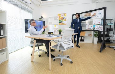 Çağdaş bir ofiste, iki üst düzey yönetici bir iş projesinin ilerleyişini izlemek ve beyin fırtınası yapmak istiyor.