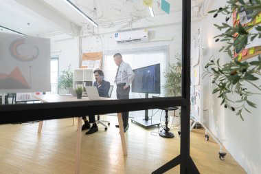 Çağdaş bir ofiste, iki üst düzey yönetici bir iş projesinin ilerleyişini izlemek ve beyin fırtınası yapmak istiyor.