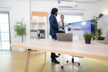 Çağdaş bir ofiste, iki üst düzey yönetici bir iş projesinin ilerleyişini izlemek ve beyin fırtınası yapmak istiyor.