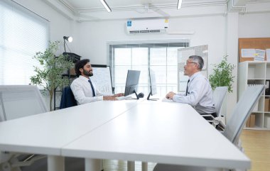 Çağdaş bir ofiste, iki üst düzey yönetici bir iş projesinin ilerleyişini izlemek ve beyin fırtınası yapmak istiyor.