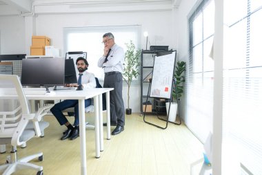 Çağdaş bir ofiste, iki üst düzey yönetici bir iş projesinin ilerleyişini izlemek ve beyin fırtınası yapmak istiyor.