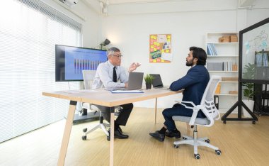 Çağdaş bir ofiste, iki üst düzey yönetici bir iş projesinin ilerleyişini izlemek ve beyin fırtınası yapmak istiyor.