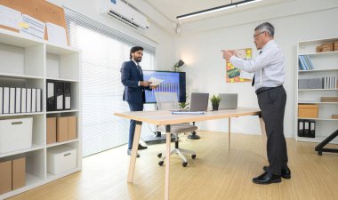 Çağdaş bir ofiste, iki üst düzey yönetici bir iş projesinin ilerleyişini izlemek ve beyin fırtınası yapmak istiyor.