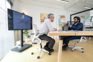 Çağdaş bir ofiste, iki üst düzey yönetici bir iş projesinin ilerleyişini izlemek ve beyin fırtınası yapmak istiyor.