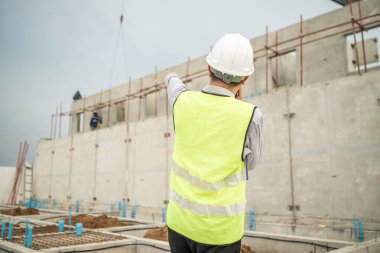Mühendisler inşaat projelerini denetliyor ve konut binalarının duvarlarının ve temellerinin inşaatını denetliyor ve denetliyor