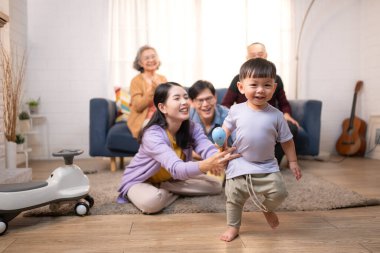 Mutlu çoklu Asyalı bir aile evde keyifle vakit geçiriyor, oyuncak bir arabayla rahat bir oturma odasında gülümsüyor ve gülümsüyor.