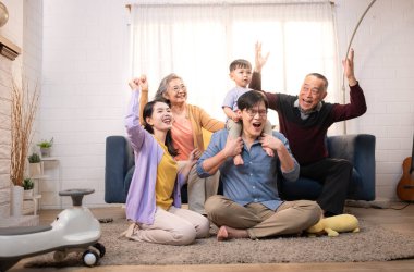 Mutlu çoklu Asyalı bir aile evde keyifle vakit geçiriyor, oyuncak bir arabayla rahat bir oturma odasında gülümsüyor ve gülümsüyor.