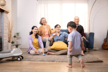 Mutlu çoklu Asyalı bir aile evde keyifle vakit geçiriyor, oyuncak bir arabayla rahat bir oturma odasında gülümsüyor ve gülümsüyor.