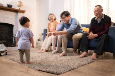 Mutlu çoklu Asyalı aile evde birlikte eğleniyor, bir bebekle tezahürat yapıyor ve gülümsüyor.