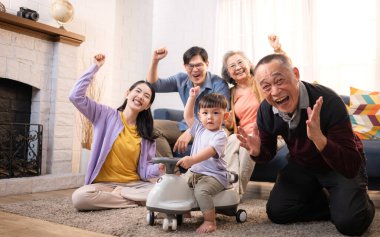 Mutlu çoklu Asyalı bir aile evde keyifle vakit geçiriyor, oyuncak bir arabayla rahat bir oturma odasında gülümsüyor ve gülümsüyor.