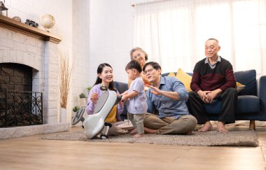 Mutlu çoklu Asyalı bir aile evde keyifle vakit geçiriyor, oyuncak bir arabayla rahat bir oturma odasında gülümsüyor ve gülümsüyor.