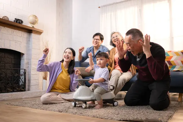 Mutlu çoklu Asyalı bir aile evde keyifle vakit geçiriyor, oyuncak bir arabayla rahat bir oturma odasında gülümsüyor ve gülümsüyor.