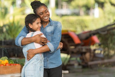 Bir tepsi meyve ve sebzeyle gülümseyen anne ve kız, öğrenme ve bahçeyle geçen bir günün tadını çıkarıyorlar.