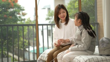 Eskrim kıyafeti giymiş bir kız, anneleriyle birlikte yaklaşan müsabaka gününe hazırlanmak için eskrim antrenmanından önce süt ve spor malzemeleri hazırlıyor.