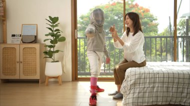 Eskrim kıyafeti giymiş bir kız, yaklaşan müsabaka gününe hazırlanmak için eskrim antrenmanından önce annesiyle spor malzemeleri hazırlıyor.